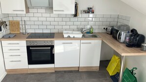 A modern kitchen with white cabinets, a built-in oven, a microwave, and a coffee maker. - Borsch Holiday Apartment 2 (Geisa)
