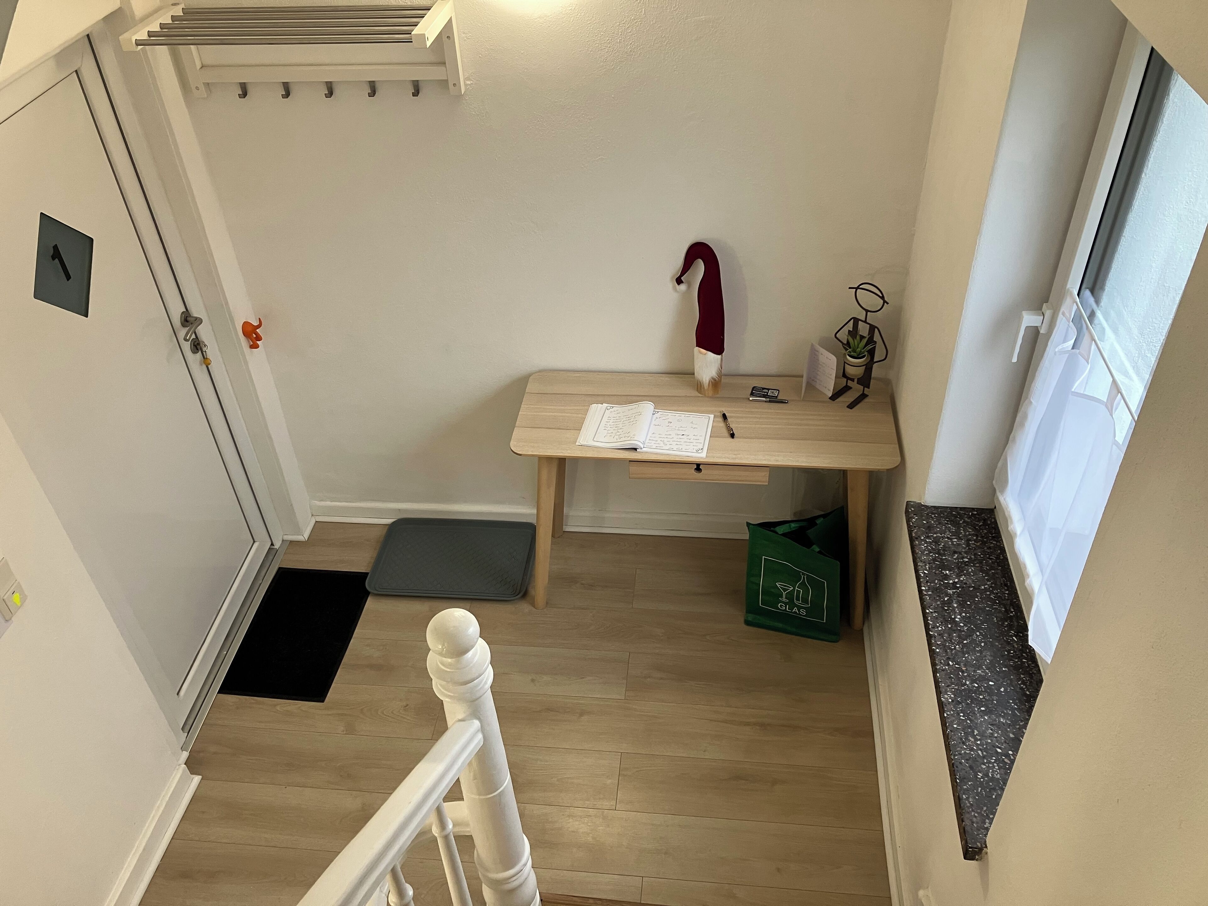 Een kleine kamer met een houten bureau, een plantje en een raam.