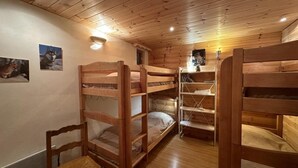 Une chambre avec un lit superposé en bois, une chaise en bois et une petite table.
