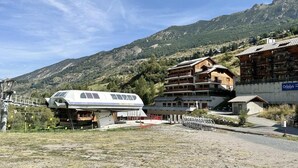 A mountain lodge with a large white building, wooden cabins, and a view of the surrounding hills. - 3rd floor, balcony, tv, ski locker, 80m², Vars (Vars)