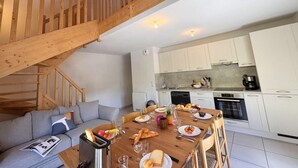 A modern kitchen with white cabinets, a dining table set with plates, glasses, and cutlery, and a wooden staircase leading to an upper level. - 3rd floor, balcony, tv, ski locker, 80m², Vars (Vars)