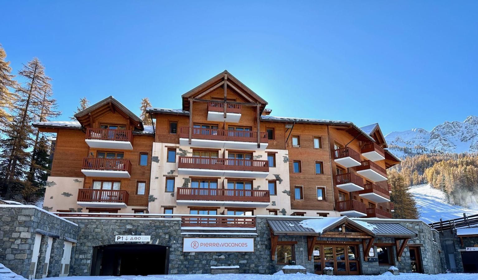 Un hôtel à plusieurs étages, doté de balcons en bois et d’une façade en pierre.
