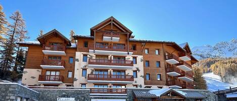 A multi-story hotel with wooden balconies and a stone facade.