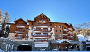 A multi-story hotel with wooden balconies and a stone facade.