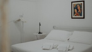 A white room with a bed, a small table, a framed picture on the wall, and a window. - Nina Delle Palme in Monopoli (Monopoli)