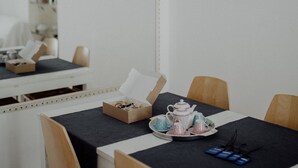 A dining area with a table set for two, featuring a teapot, cups, and saucers. There are chairs around the table, and a mirror on the wall. - Nina Delle Palme in Monopoli (Monopoli)
