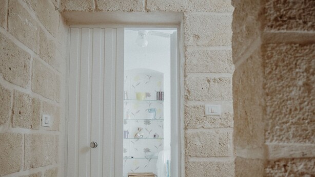 A narrow hallway with a white door leading to a room with shelves and a small table. - Nina Delle Palme in Monopoli (Monopoli)