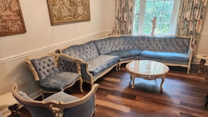A room with a large L-shaped blue sofa, a matching armchair, and a round coffee table.
