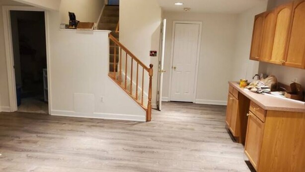 A spacious kitchen with wooden cabinets and a wooden staircase leading to another level.
