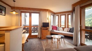 Una habitación acogedora con un banco de madera, un sofá con cojines, una mesita y un televisor sobre un mueble de madera.