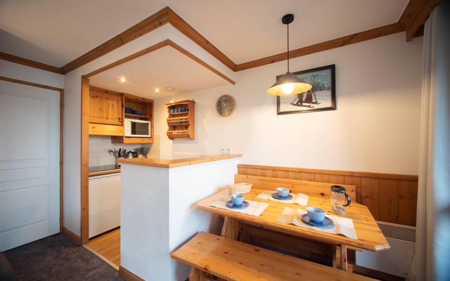 Une cuisine chaleureuse avec des meubles en bois, un four à micro-ondes encastré et un coin repas comprenant un banc et une table en bois.