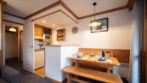 Una cocina acogedora con detalles de madera, una zona de comedor con banco y un microondas.