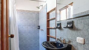 Une salle de bain avec un lavabo noir, des toilettes, une douche et un miroir.