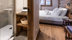 A bedroom with a wooden floor, a bed with white linens, a bedside table, and a window with curtains. - 100m from ski slopes, 4th floor, view mountain, balcony, tv, 200m², Champagny-en-Vanoise (Champagny-en-Vanoise)