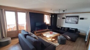 A modern living room with a large sofa, a coffee table, and a TV.