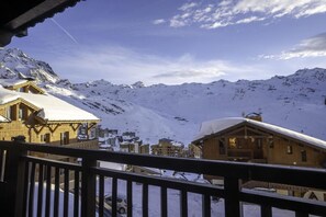 A wooden chalet with a snow-covered roof, a balcony, and a view of snow-covered mountains in the background. - 100m from ski slopes, 3rd floor, balcony, fireplace or stove, tv, ski locker, 160m², Val Thorens (Val Thorens)