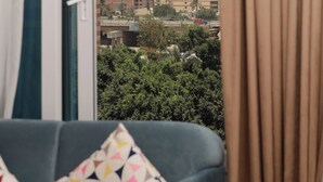 Une pièce avec vue sur une pyramide, un canapé avec des coussins à motifs et un rideau.