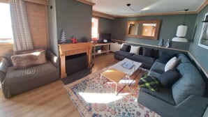 Un salon chaleureux avec une cheminée, un canapé, une table basse et un téléviseur.