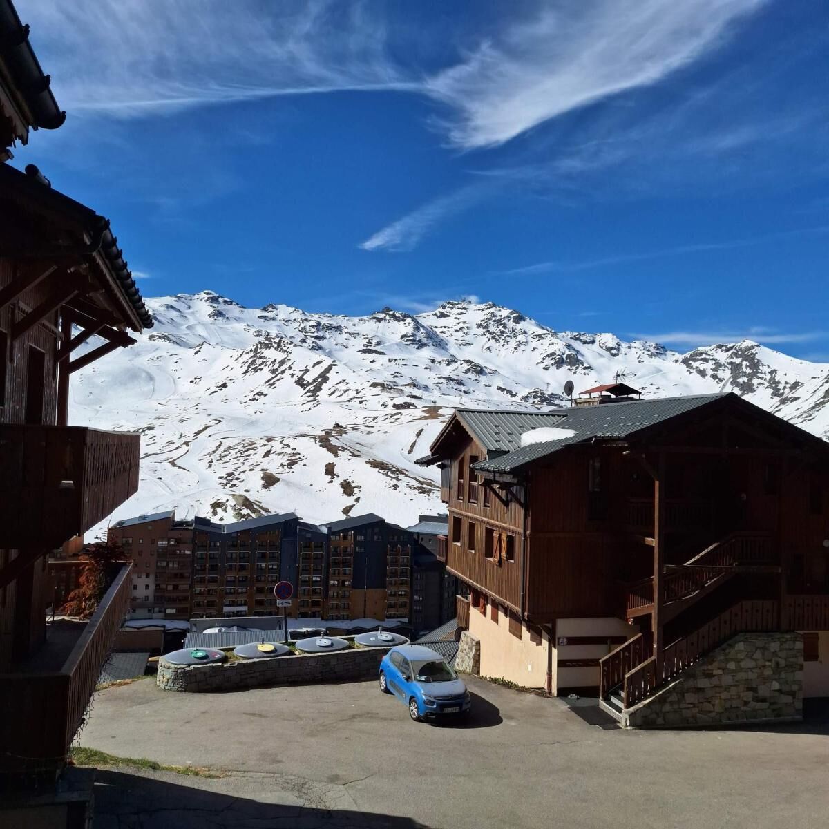 Un refugio de montaña con un telesilla, picos nevados y un cielo azul despejado.