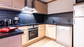 Una cocina moderna con armarios de madera, un salpicadero de mármol negro, electrodomésticos de acero inoxidable y un horno empotrado.