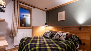 Un dormitorio acogedor con colcha a cuadros, cabecera de madera y ventana con vistas.