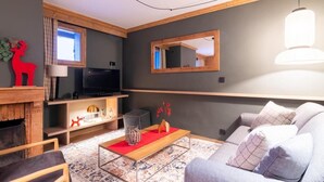 Una sala de estar moderna con chimenea, televisor, sofá y elementos decorativos.