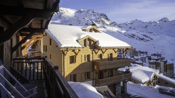 A wooden chalet with a balcony, set against a snowy mountain backdrop. - 100m from ski slopes, 1st floor, balcony, fireplace or stove, tv, ski locker, 66m², Val Thorens (Val Thorens)