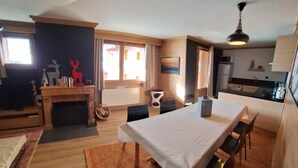 A compact living space with a dining area, a fireplace, a kitchen, and a ceiling fan. - 100m from ski slopes, 1st floor, balcony, fireplace or stove, tv, ski locker, 66m², Val Thorens (Val Thorens)