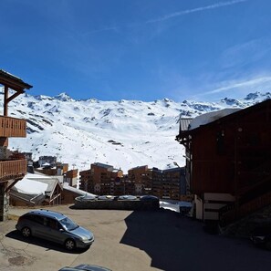 A snowy mountain town with a parking area, buildings, and a clear blue sky. - 100m from ski slopes, Ground floor, terrace, tv, ski locker, 48m², Val Thorens (Val Thorens)