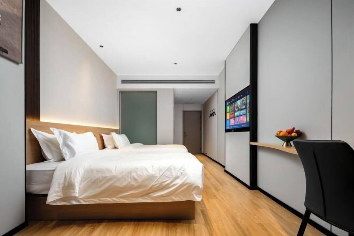 Una habitación de hotel moderna con una cama, un escritorio y un televisor mostrando un menú.