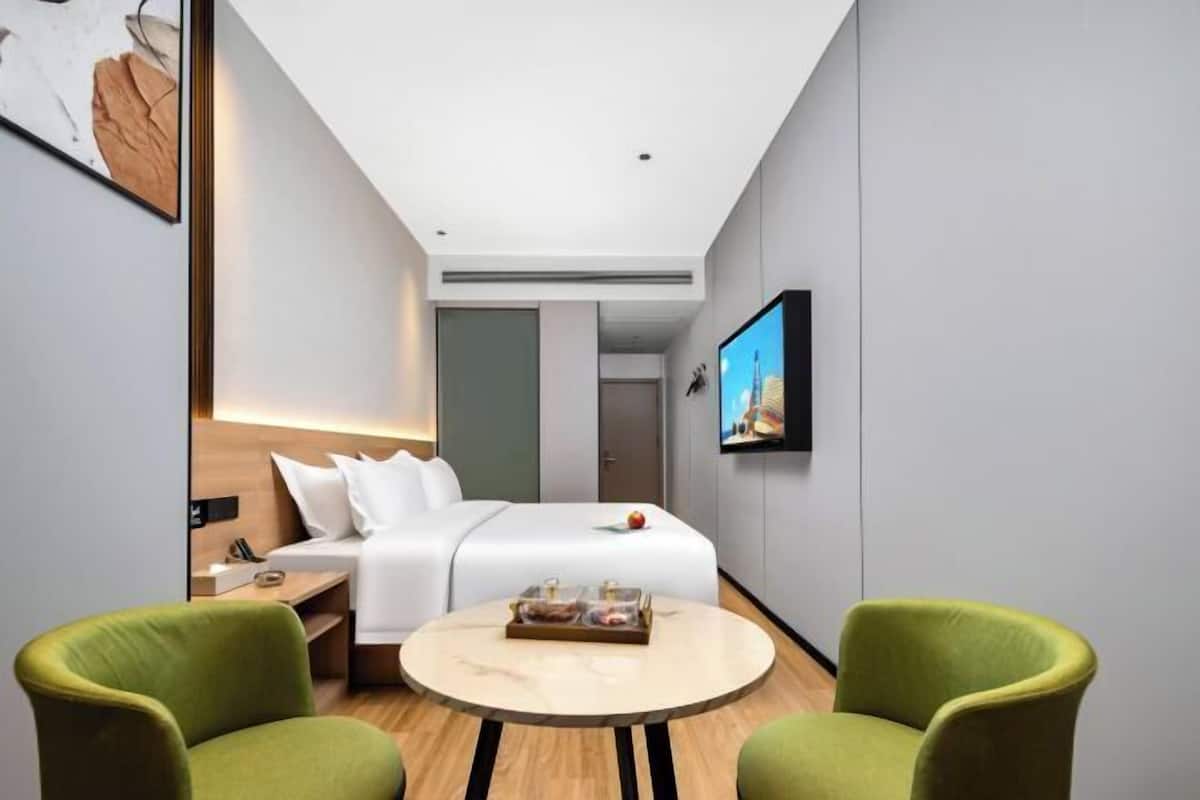Habitación de hotel con cama, televisión, una mesa redonda y dos sillas.