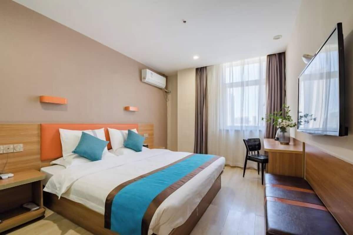 Habitación de hotel con una cama grande, un escritorio, una silla y un televisor.