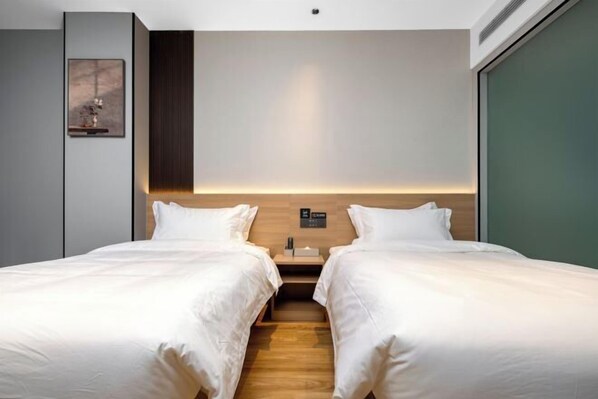 A hotel room with two beds, a wooden headboard, a nightstand, and a framed picture on the wall. - City 118 Chain Hotel Zhengzhou Economic Development Zone (Zhengzhou)
