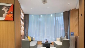 A modern living room with a curved sofa set, a small coffee table, and a bookshelf. - City 118 Chain Hotel Zhengzhou Economic Development Zone (Zhengzhou)