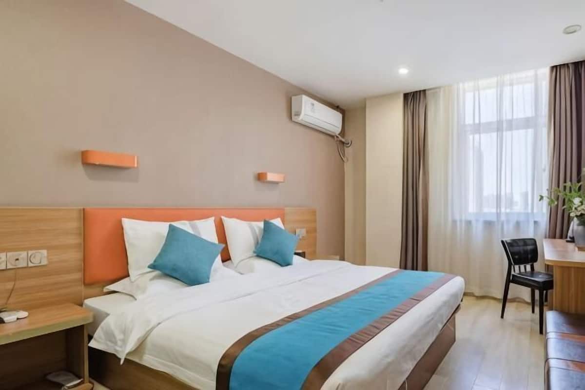 Una habitación de hotel con una cama, mesitas de noche, un escritorio y una silla.