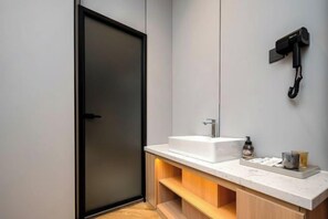 A modern bathroom with a large mirror, a white sink, and a hairdryer mounted on the wall. - City 118 Chain Hotel Zhengzhou Economic Development Zone (Zhengzhou)