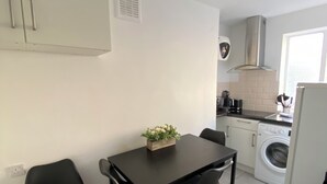 Une cuisine compacte comprenant une table à manger, des chaises, un lave-linge et une petite fenêtre.