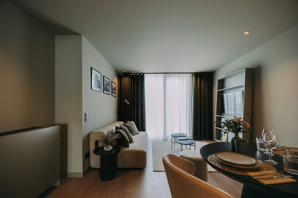 A modern living room with a sofa, coffee table, and dining area with a table set for two.