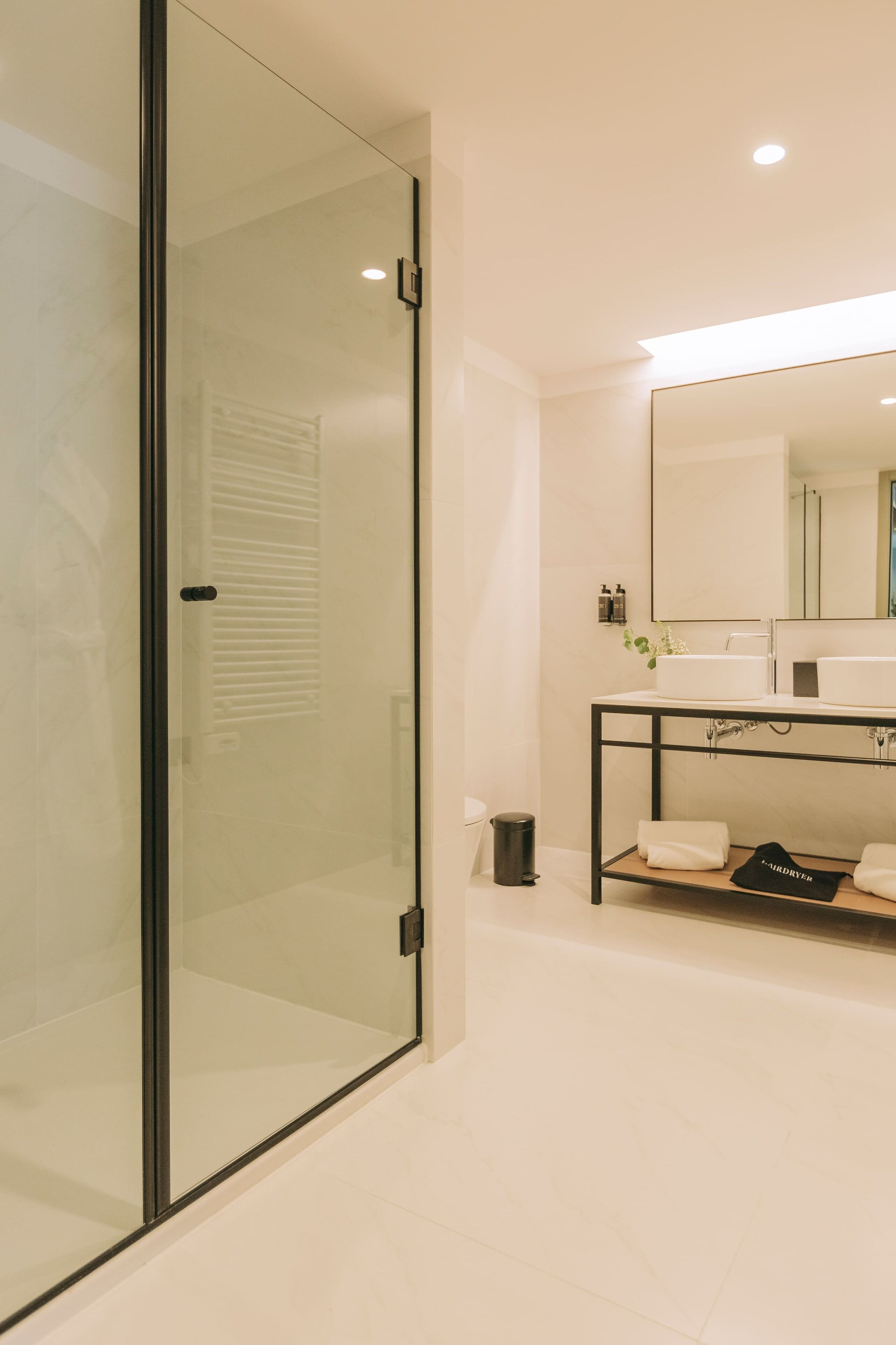 Une salle de bain moderne avec une douche à parois de verre, un lavabo blanc et un miroir au-dessus du lavabo.