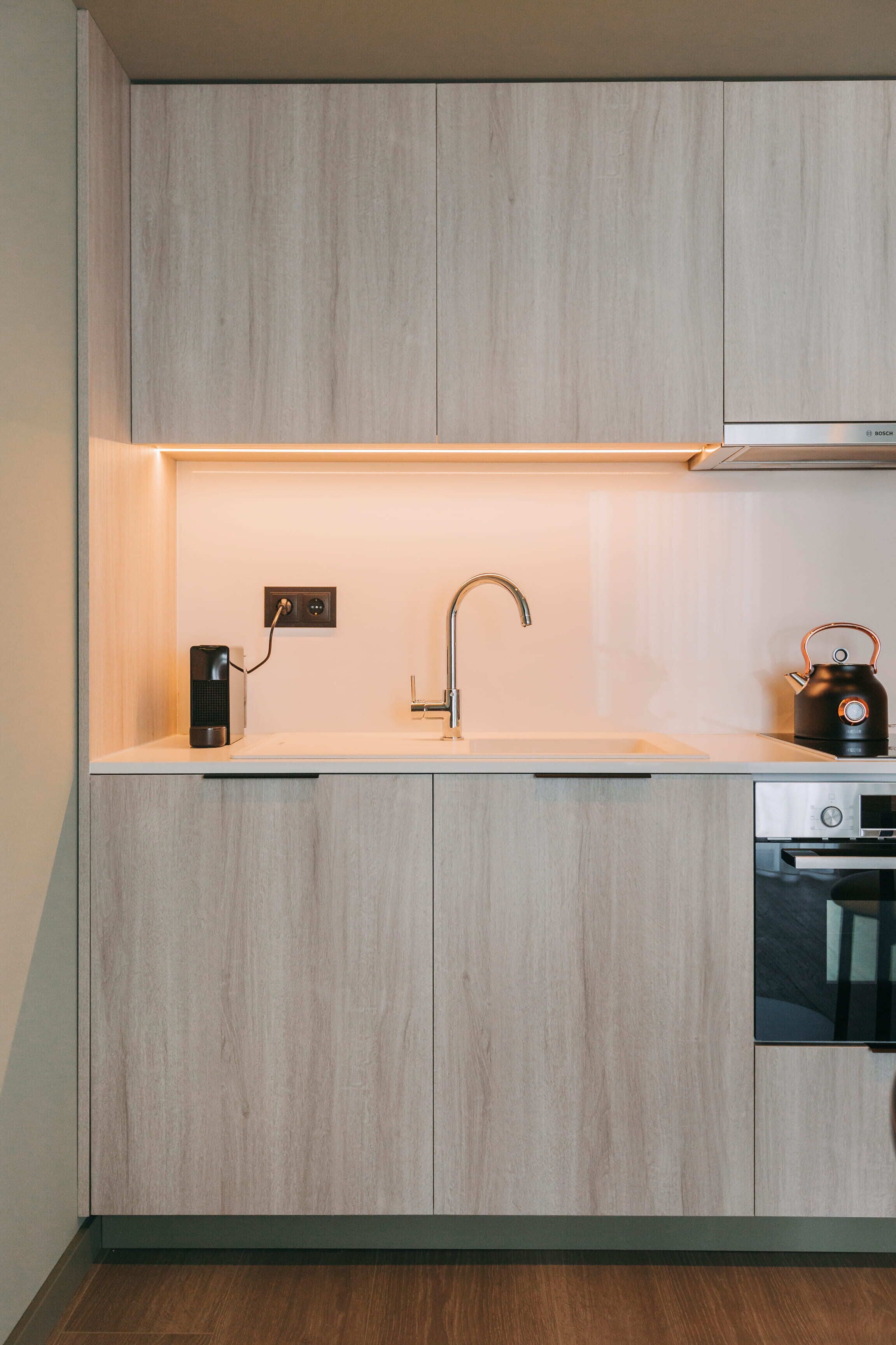 A modern kitchen with a built-in sink, a kettle, and a Bosch appliance.