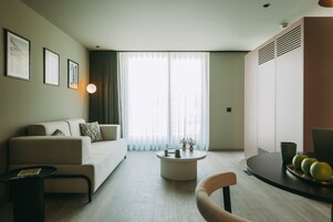 En moderne stue med sofa, sofabord og et spiseområde med en tallerken æbler.