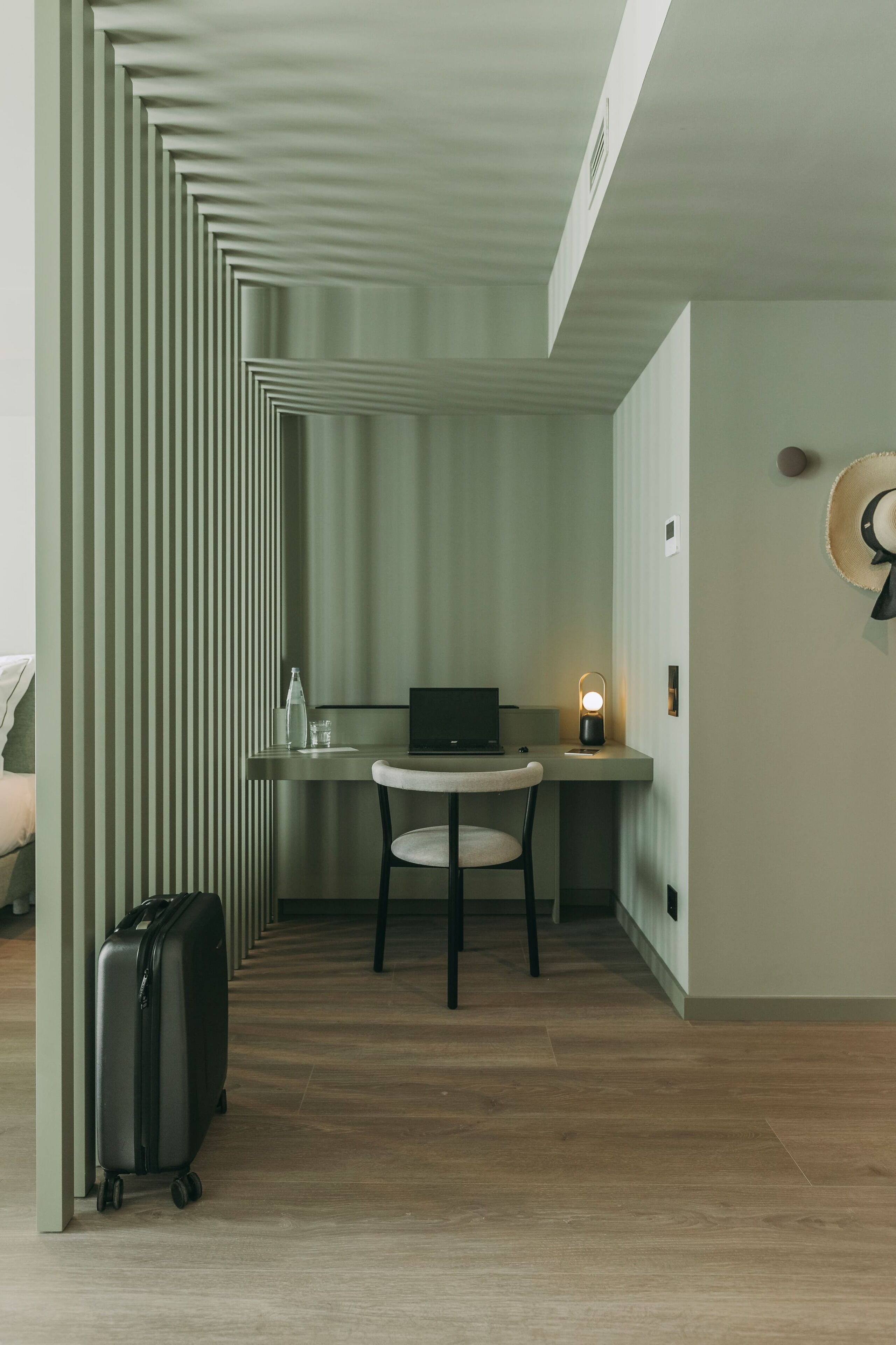 A compact room with a desk, chair, and a suitcase.
