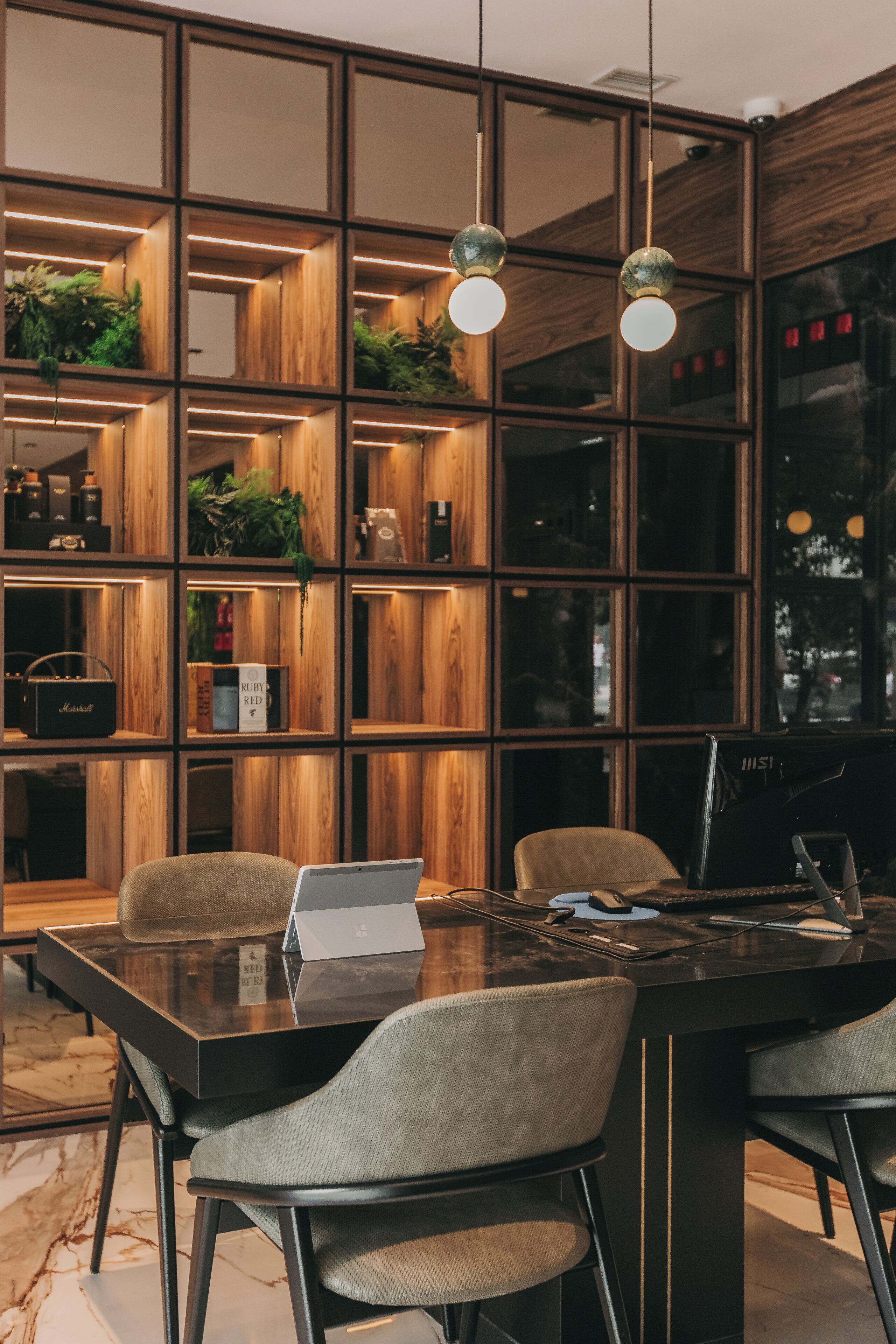 Un interior moderno con una estantería de madera, una mesa de vidrio y dos sillas.