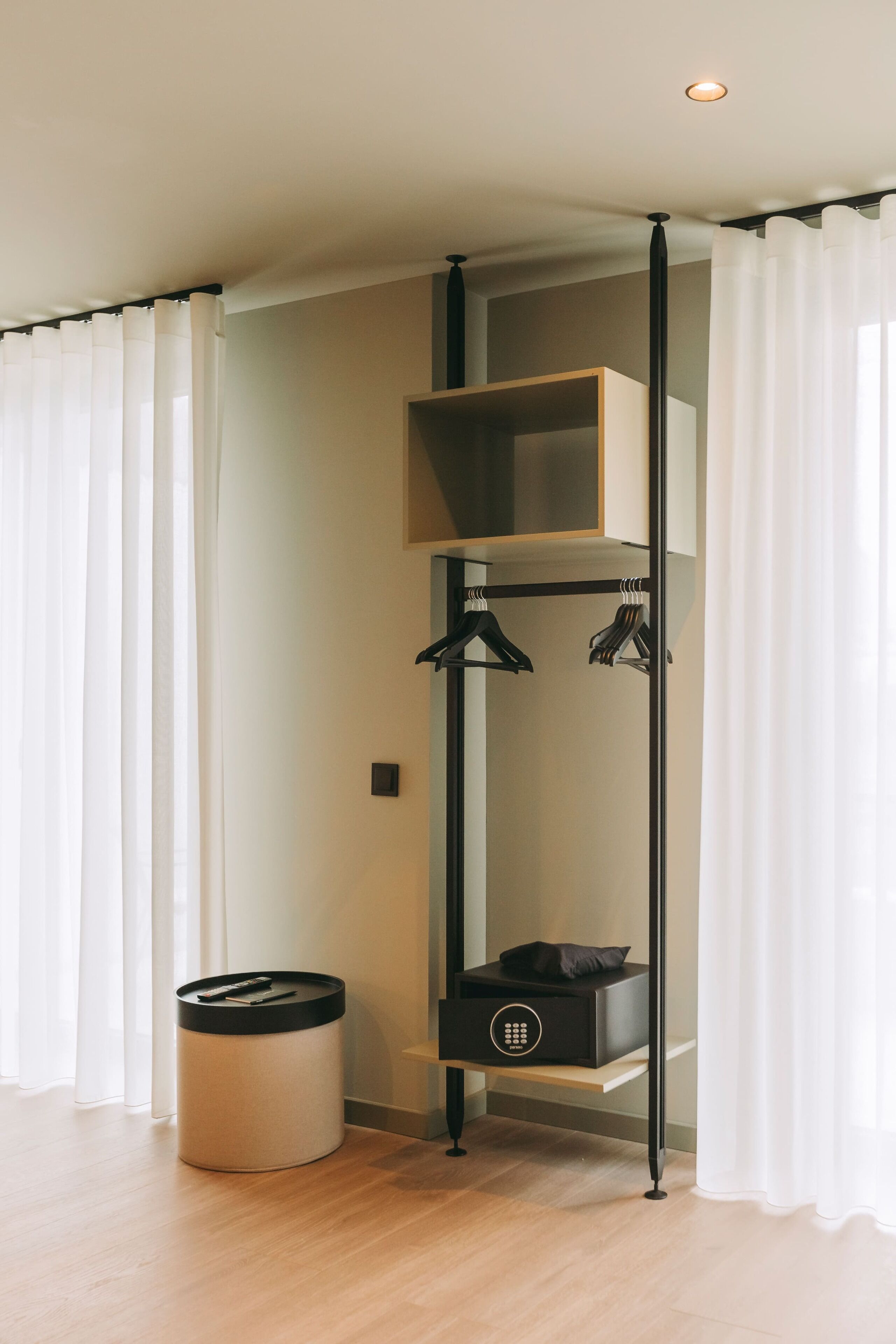 A modern room with a built-in wardrobe, a small trash bin, and a shelf unit.