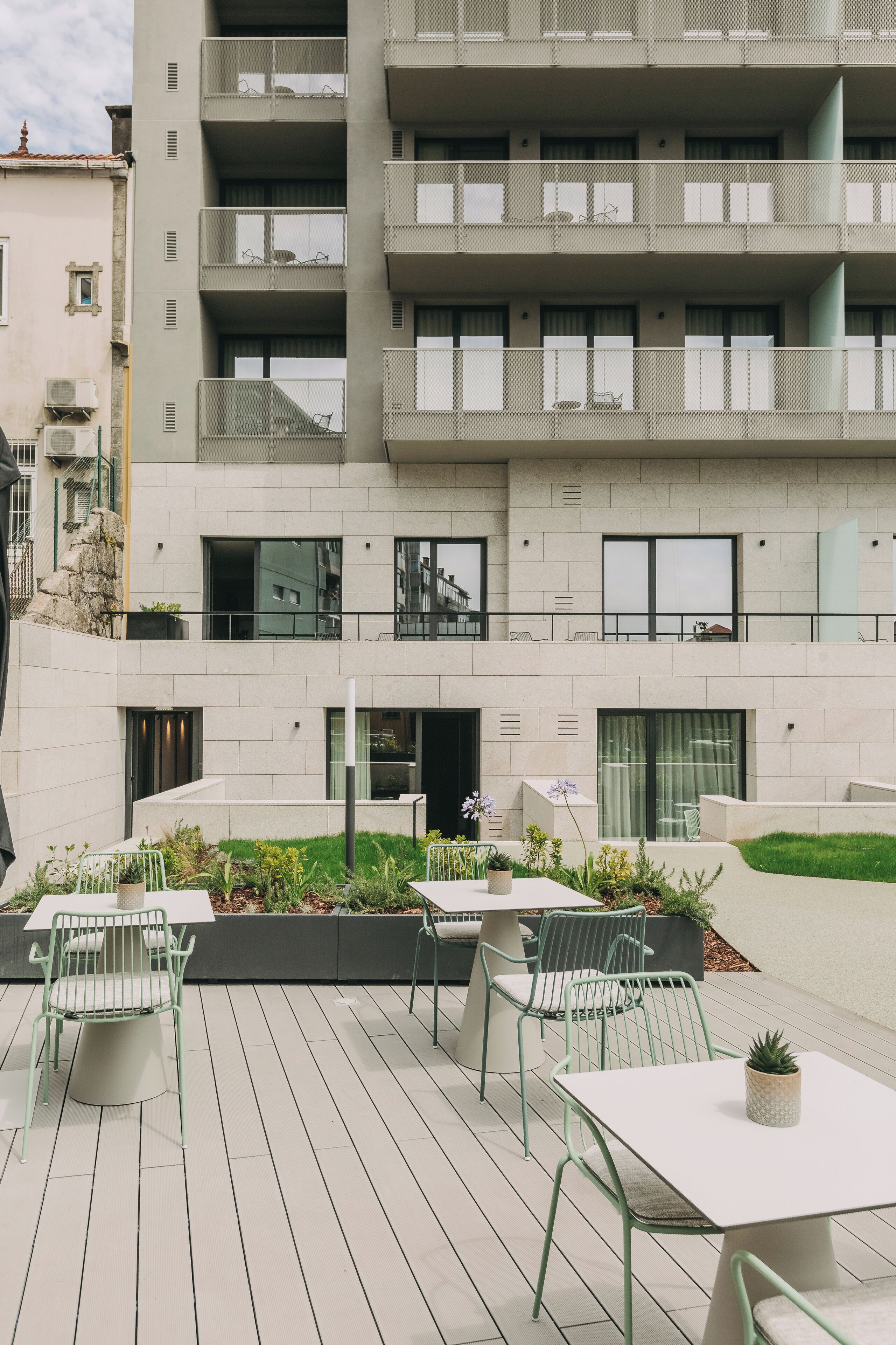 Un immeuble d’appartements moderne doté d’un espace extérieur aménagé avec des sièges et d’un jardin.