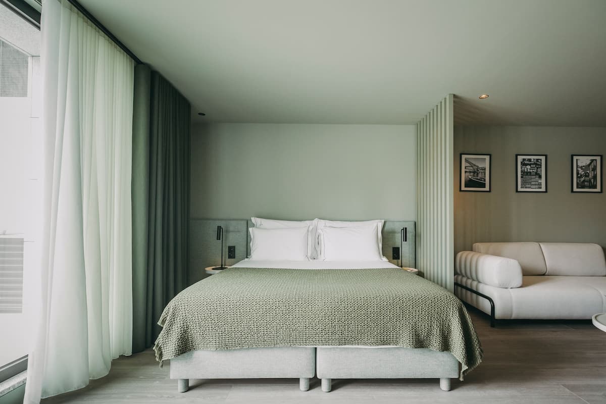 A modern bedroom with a large bed, a sofa, and a nightstand.