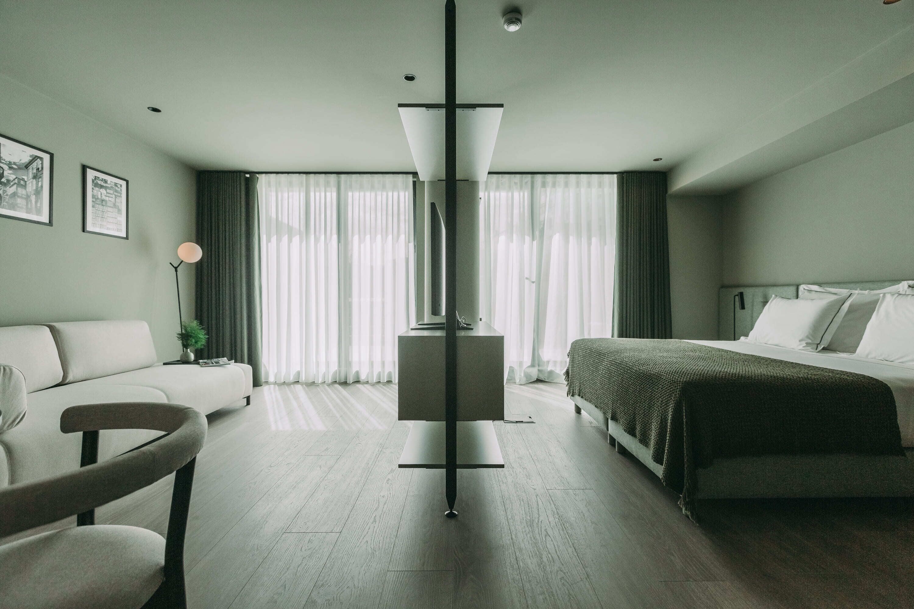 Ein modernes Hotelzimmer mit Bett, Sofa, Schreibtisch und Stuhl.