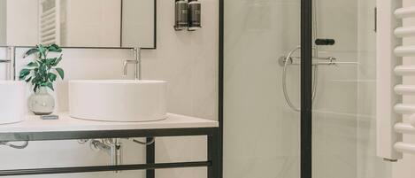 A modern bathroom with a glass-enclosed shower, a white sink, and a mirror above it.
