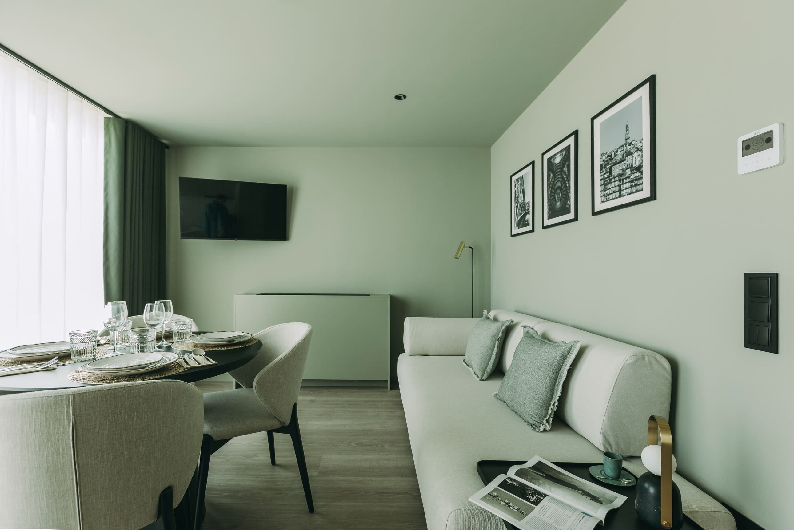 A modern living room with a dining area, a flat-screen TV, and framed pictures on the wall.