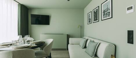 A modern living room with a dining area, a flat-screen TV, and framed pictures on the wall.